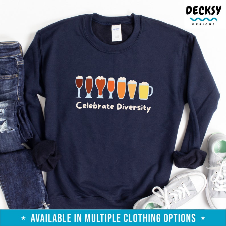 May include: A navy blue sweatshirt featuring a graphic of different beer glasses in shades of brown and yellow. The white text "Celebrate Diversity" is printed below. The sweatshirt is shown with jeans and trainers.