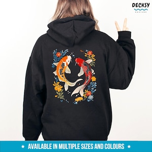 May include: Black hoodie featuring a design of two koi fish swimming in opposite directions, surrounded by colourful flowers. The design is on the back of the hoodie.