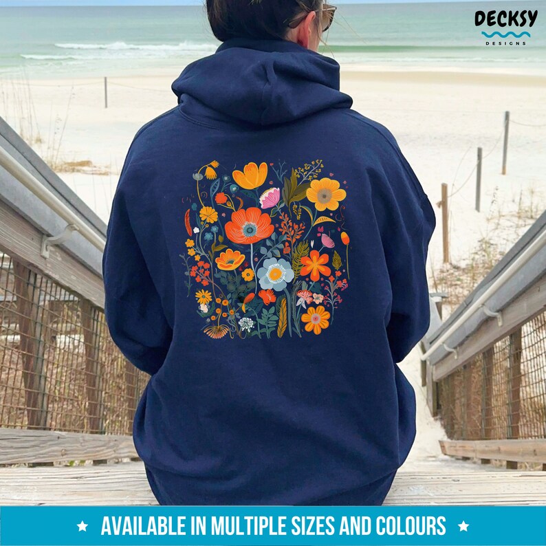May include: A navy blue hoodie with a floral print on the back. The print features a variety of flowers in shades of orange, yellow, pink, blue, and green.