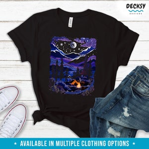 May include: A black t-shirt with a colorful illustration of a campsite in the mountains at night. The illustration features a tent, a campfire, trees, and a full moon in the sky.