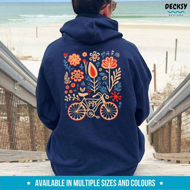 Op de afbeelding: Donkerblauwe hoodie met een bloemen- en fietsontwerp op de rug. Het ontwerp is in de kleuren rood, oranje, geel en blauw.