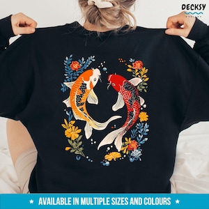 May include: Black sweatshirt featuring a design of two orange and red koi fish swimming in a circle of colourful flowers.