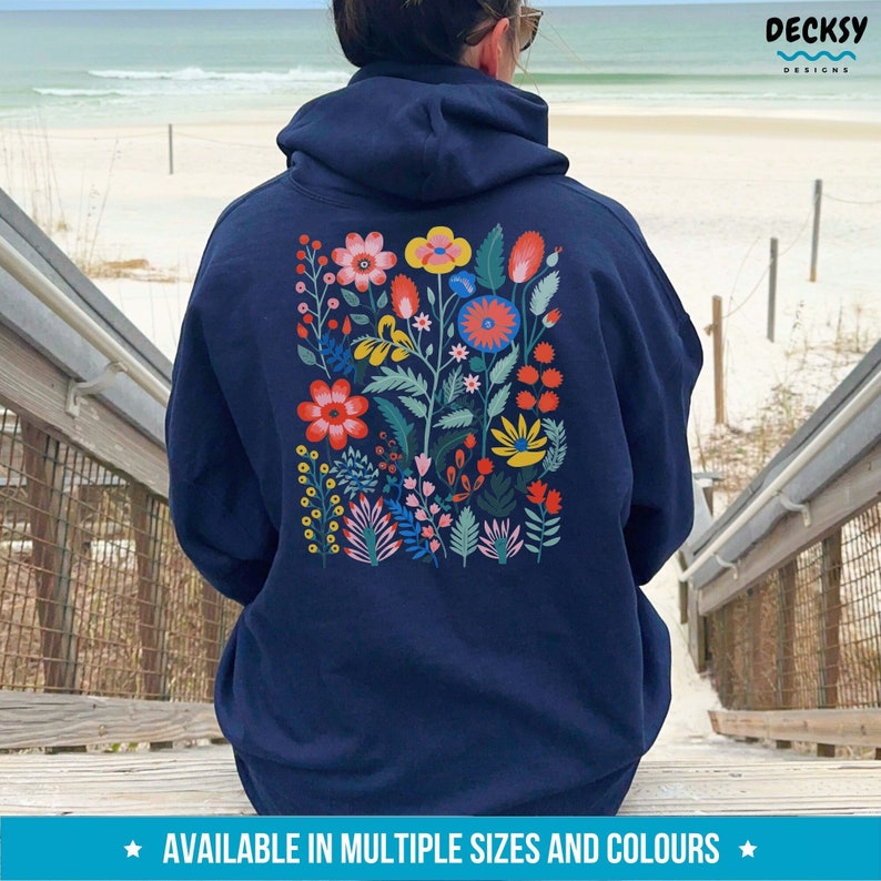 May include: A navy blue hoodie with a colorful floral design on the back. The design features flowers in shades of red, yellow, blue, and green. The hoodie is available in multiple sizes and colors.