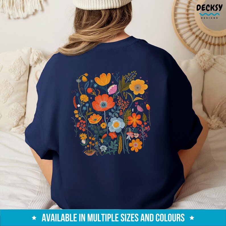 May include: A navy blue sweatshirt with a colorful floral print on the back. The print features a variety of flowers in shades of orange, yellow, red, pink, and blue.