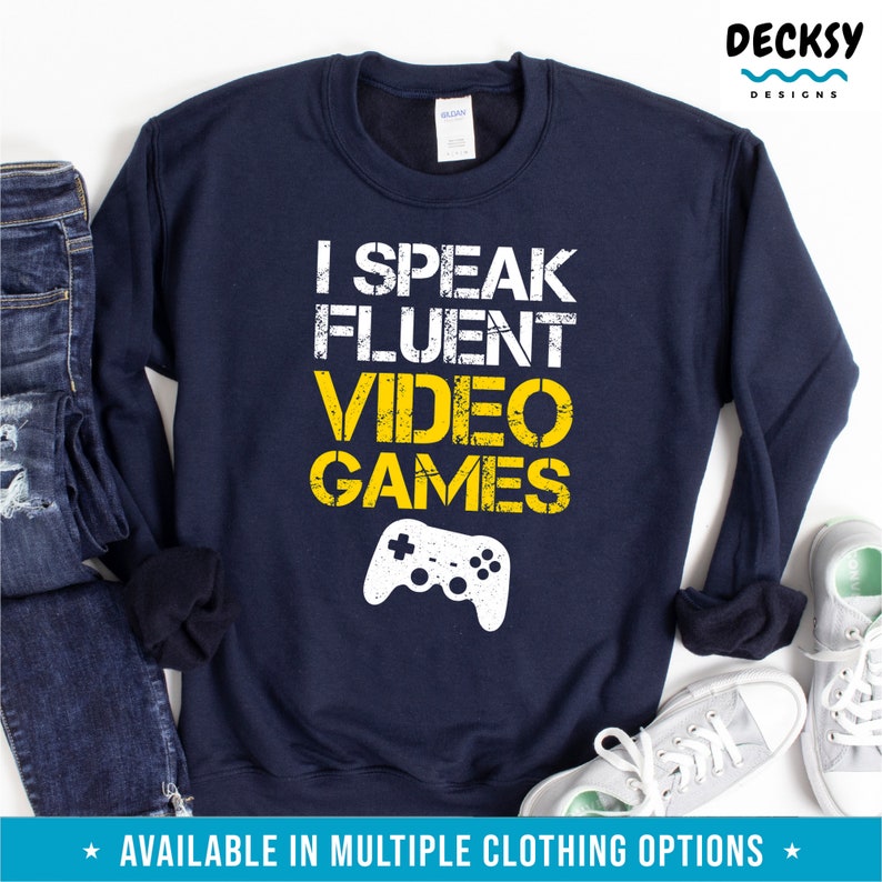 May include: A navy blue sweatshirt with a yellow graphic that says "I speak fluent video games" and a white video game controller graphic.
