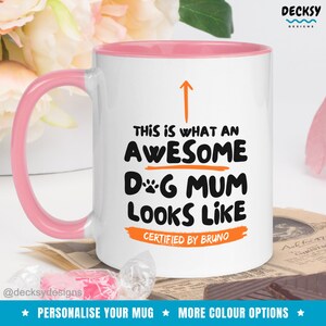 May include: White ceramic mug with a pink rim. The mug has a black and orange design that says "This is what an awesome dog mum looks like. Certified by Bruno."