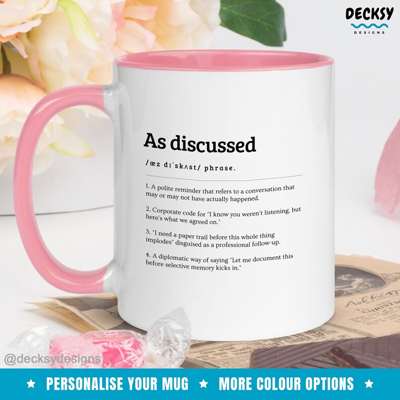 Peut inclure: Mug en c&eacute;ramique blanche avec int&eacute;rieur et anse roses. La tasse pr&eacute;sente l'expression "As discussed" avec une d&eacute;finition et plusieurs points num&eacute;rot&eacute;s. Le bas de la tasse porte le texte "Personalise your mug" et "More colour options".