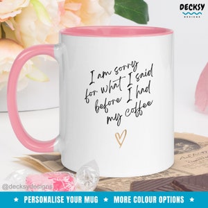 May include: White ceramic coffee mug with a pink rim and handle. The mug has black text that reads "I am sorry for what I said before I had my coffee" with a gold heart below the text.