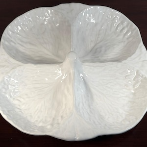 May include: White ceramic serving dish with a three-section design. The dish is shaped like a cabbage leaf, with detailed veining and a glossy finish. Ideal for serving appetizers or snacks.