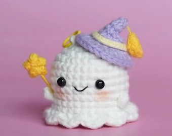 May include: A white crocheted ghost wearing a purple witch hat with a yellow star wand. The ghost has a smiling face with black eyes and pink cheeks.