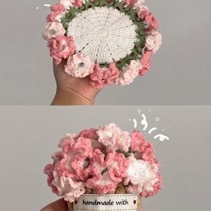 Könnte beinhalten: Handgefertigter Häkeluntersetzer mit weißer Mitte, grünem Rand und rosa-weißen blütenartigen Verzierungen. Das zweite Bild zeigt einen gehäkelten Blumenkorb mit dem Text "handmade with".