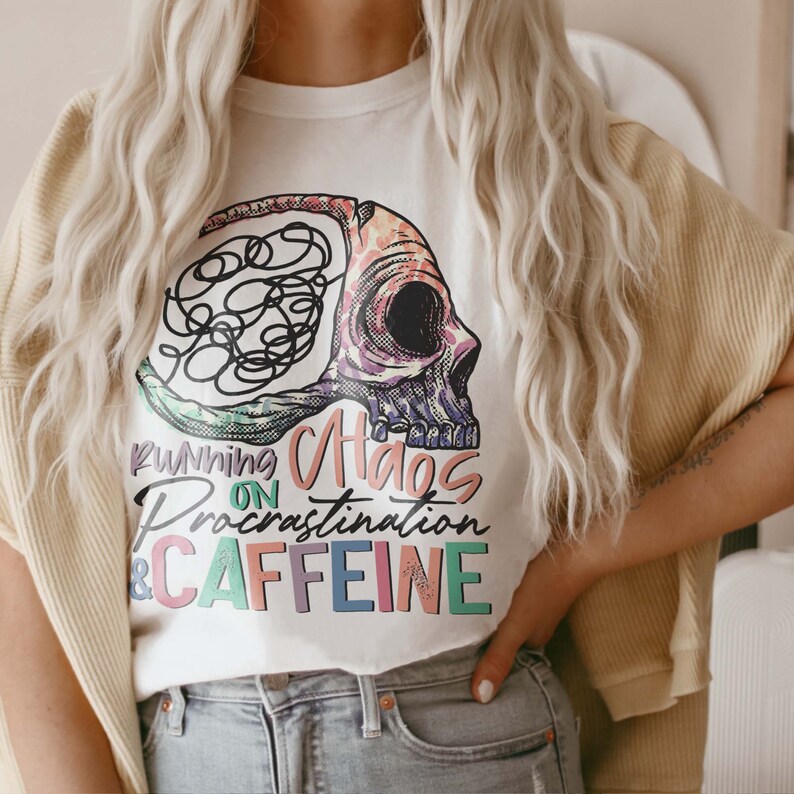 K&ouml;nnte beinhalten: Wei&szlig;es T-Shirt mit einer bunten Grafik eines Sch&auml;dels mit verschlungenen Linien im Inneren. Der Text "Running on Chaos Procrastination & Caffeine" ist unter dem Sch&auml;del aufgedruckt.