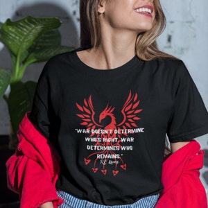 May include: Black t-shirt featuring a red phoenix graphic and the quote "WAR DOESN'T DETERMINE WHO'S RIGHT. WAR DETERMINES WHO REMAINS." by R.E. Kuang.