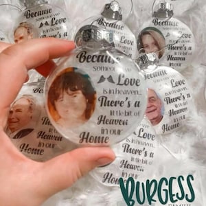 Peut inclure: Boules de Noël en verre transparent avec photos et texte. Le texte dit "Parce que quelqu'un qu'on aime est au ciel, il y a un petit coin de paradis dans notre maison." Les boules ont des bouchons argentés.