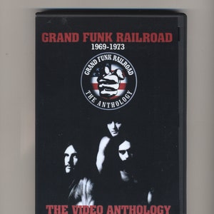 May include: A black DVD case featuring the text "GRAND FUNK RAILROAD 1969-1973" in red. The cover includes a band logo and a photo of the band members. The text "THE VIDEO ANTHOLOGY" is also displayed.