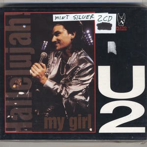 May include: A CD case with a black background featuring a man holding a microphone. The text "Hallelujah" is vertically aligned on the left, and "my girl" is at the bottom. The words "MINT SILVER 2CD" are at the top.