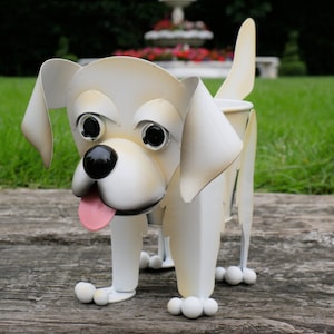 May include: White metal dog planter with black eyes and a pink tongue. The dog is standing on a wooden surface.