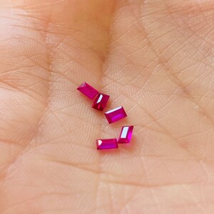 Könnte beinhalten: Fünf kleine, rechteckige, rubinrote Edelsteine auf einer Hand.