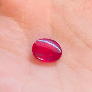 以下が含まれることがあります： 明るい赤色の丸い宝石のクローズアップ。宝石は滑らかで光沢があり、わずかに光を反射しています。