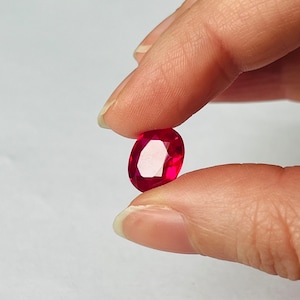 Peut inclure: Une pierre précieuse ovale de couleur rouge foncé avec des facettes.