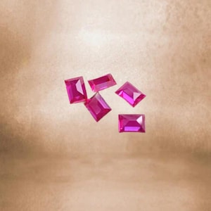 Op de afbeelding: Vijf roze rechthoekige edelstenen op een lichtbruine achtergrond.