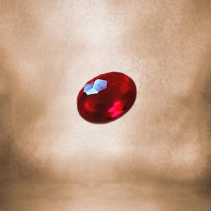 Può includere: Una pietra preziosa di colore rosso intenso con taglio a faccette. La pietra preziosa ha una forma ovale e un'alta lucidatura.