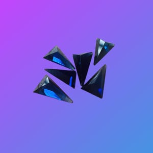 May include: A group of six dark blue triangular rhinestones, scattered on a purple and blue gradient background.