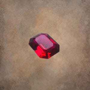 Puede incluir: Una piedra preciosa de color rojo intenso con forma rectangular y una superficie lisa y pulida.