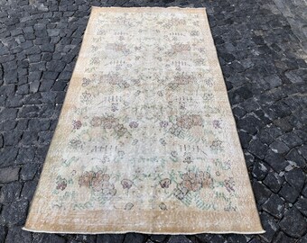 May include: A vintage cream-colored rug with a floral pattern in shades of brown, green, and pink. The rug has a distressed look and is perfect for adding a touch of vintage charm to any room.