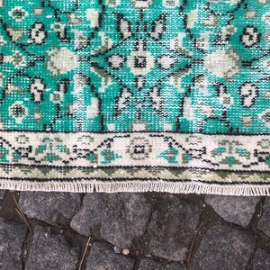 May include: A teal and white patterned rug with a fringe border. The rug has a traditional design with intricate details.