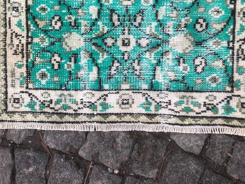 May include: A teal and white patterned rug with a fringe border. The rug has a traditional design with intricate details.