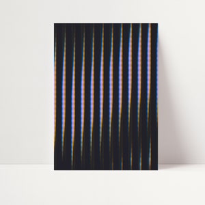 Vertical art print with vertical abstract lines. The background is black–dark grey and the lines are blue-white-yellow.