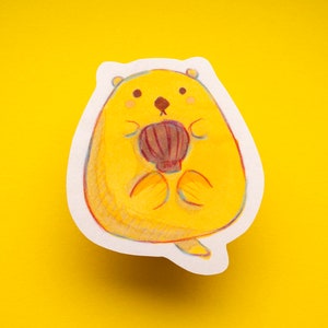 May include: A yellow cartoon sticker of a round, chubby animal with a red shell on its belly. The animal has a small nose and two black eyes.