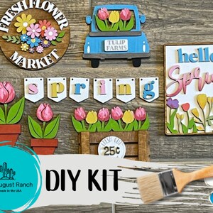 May include: DIY craft kit featuring a variety of spring-themed wooden cutouts, including a flower market sign, a truck with tulips, a "hello spring" sign, a banner with the word "spring", and a flower pot with tulips. The kit also includes paint and a paintbrush.