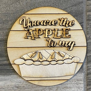 May include: Wooden round sign with the text "You are the APPLE to my" and a cutout of an apple pie.