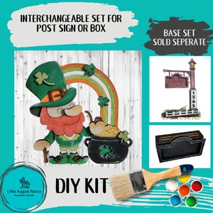 May include: DIY kit for a leprechaun holding a pot of gold with a rainbow and shamrocks. The kit includes a wooden cutout of the leprechaun, pot of gold, and rainbow, along with paint and a paintbrush. The base set is sold separately.