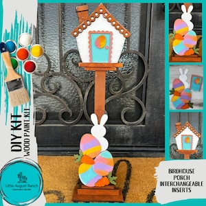 May include: DIY wood paint kit featuring a birdhouse porch with interchangeable inserts. The kit includes a wooden birdhouse, a wooden bunny, and a set of colorful eggs. The birdhouse is painted white with a blue door and a brown roof. The bunny is white with a brown base. The eggs are painted in various shades of pink, blue, yellow, and green. The kit is perfect for decorating your home for Easter.