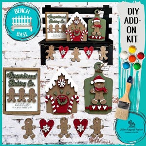 May include: DIY gingerbread house add-on kit with a gingerbread baking company sign, a gingerbread house, a gingerbread man cutting board, and a gingerbread man banner. The kit includes paint pots in various colors and a paintbrush.