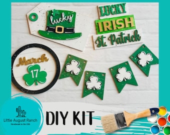 May include: DIY craft kit for St. Patrick's Day, featuring a green shamrock design, a sign that says "Lucky Irish St. Patrick", a round sign with "March 17", and a paintbrush and paint.