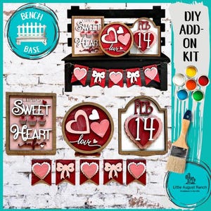 May include: DIY Valentine's Day add-on kit with a wooden bench base, heart-shaped signs, a banner, and paint pots. The signs feature the text "Cupid's Sweet Heart", "Love", and "Feb 14".