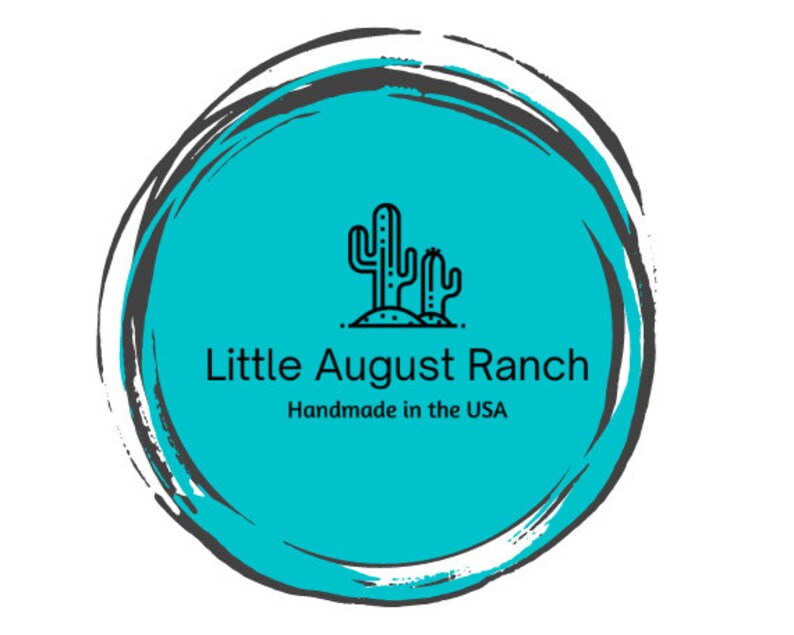 May include: A turquoise circle with a black outline and a white brushstroke effect. Inside the circle is a black line drawing of two cacti with the text "Little August Ranch" and "Handmade in the USA" below.