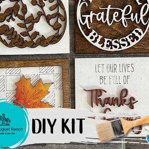 May include: DIY kit for creating four wooden signs with fall-themed designs. The signs feature phrases like "Grateful Blessed" and "Let our lives be full of thanks". The kit includes paint, brushes, and stencils.