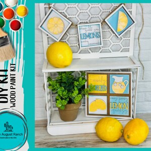 May include: DIY wood paint kit with four lemon-themed signs. The signs feature phrases like "When life gives you lemons, make lemonade" and "Freshly Squeezed". The kit includes paint and brushes.