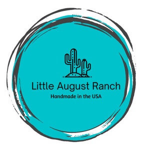 K&ouml;nnte beinhalten: Ein t&uuml;rkisfarbener Kreis mit schwarzem Umriss und einem wei&szlig;en Pinselstrich-Effekt. Im Inneren des Kreises befindet sich eine schwarze Linienzeichnung von zwei Kakteen mit dem Text "Little August Ranch" und "Handmade in the USA" darunter.