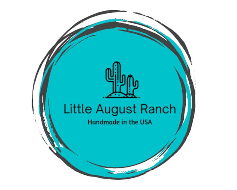 K&ouml;nnte beinhalten: Ein t&uuml;rkisfarbener Kreis mit schwarzem Umriss und einem wei&szlig;en Pinselstrich-Effekt. Im Inneren des Kreises befindet sich eine schwarze Linienzeichnung von zwei Kakteen mit dem Text "Little August Ranch" und "Handmade in the USA" darunter.