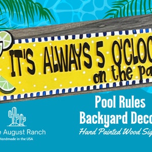 May include: Hand-painted wooden sign with the text "IT'S ALWAYS 5 O'CLOCK on the patio". The sign is yellow with white polka dots and blue and white stripes. It features a margarita glass with a lime wedge. The sign is made by Little August Ranch and is handmade in the USA.