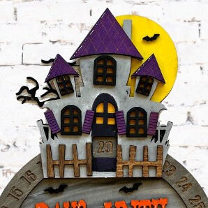 May include: A wooden Halloween countdown calendar with a purple and gray haunted house, a yellow moon, and bats. The calendar features the numbers 1 to 31, with the current day highlighted. The text "Days Until Halloween" is printed on the calendar.