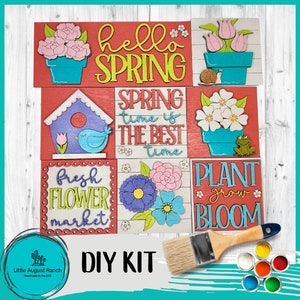 May include: A DIY kit featuring wooden spring-themed signs with floral and seasonal designs. The signs include phrases like "Hello Spring," "Fresh Flower Market," and "Plant Grow Bloom." A paintbrush and paint pots are also included.