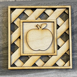 May include: A wooden cutout of an apple inside a square frame with a lattice design.