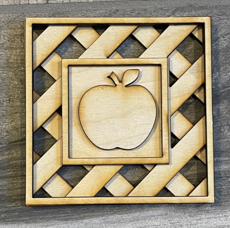 May include: A wooden cutout of an apple inside a square frame with a lattice design.